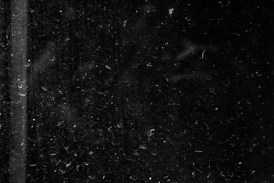 Dark dust overlay texture. Dirty glass surface with scratches, smudges and scattered particles.