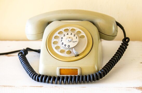 Brazil, December 26, 2016: Vintage Ericsson rotary dial telephone, beige in color, on a rustic wooden surface.