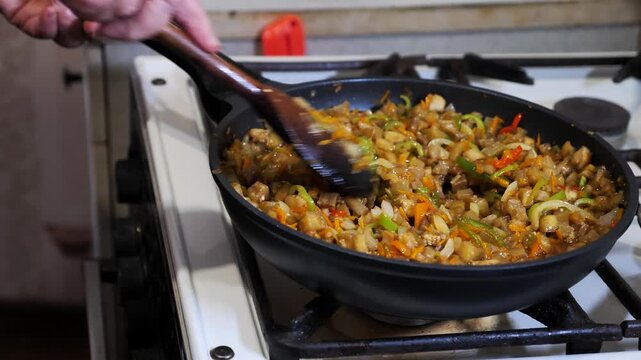 Close-up of an old woman's hand preparing vegetable stew in a frying pan on a gas stove. Poverty, destitution. Social inequality. Small pension.