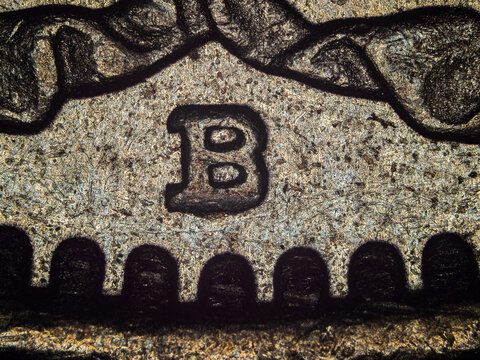 Engraved letter B relief on Swiss franc coin under microscope