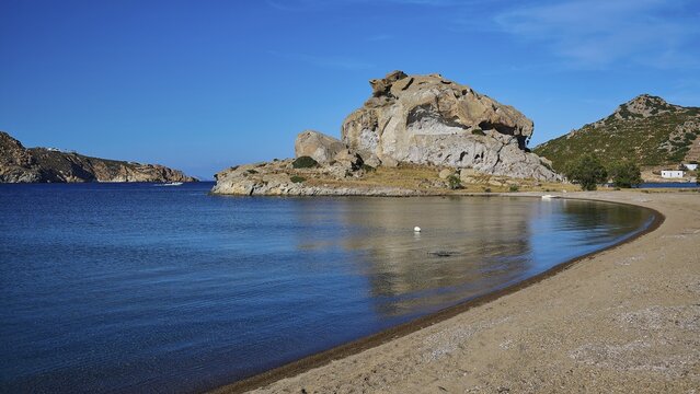 A quiet beach with a rock formation and calm waters under a clear blue sky, Petras Beach, Kalikatsou Rocks, Patmos, Dodecanese, Greek Islands, Greece