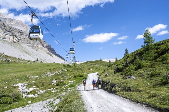 Hikers on a road, climbing to Rifugio Graffer below the Grost&eacute; cable car, Brenta, Brenta-Adamello Natural Park, Trentino, Italy