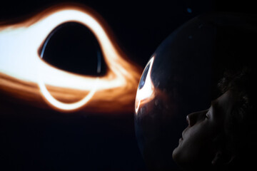 Conceptual profile portrait of a young boy astronaut in a glass helmet looking at a glowing black hole in deep space © Stefano Pessina