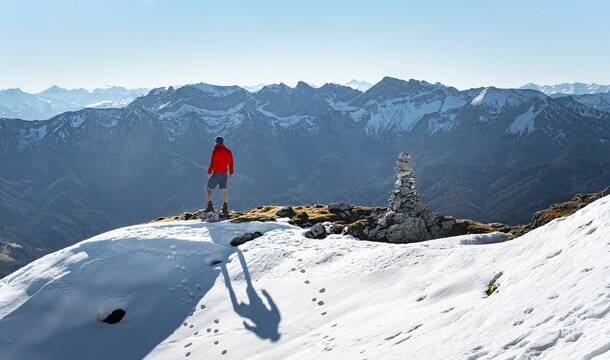 Mountaineer next to a cairn, in front of snowy mountains of the Rofan, hiking trail to the Guffert with first snow, in autumn, Brandenberg Alps, Tyrol, Austria