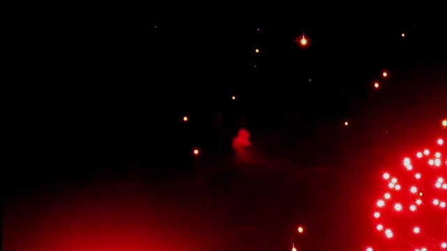 Witness a mesmerizing display of crimson fireworks illuminating the night. This festive show brings joy and excitement to a New Year's celebration, painting the sky with vibrant colors.