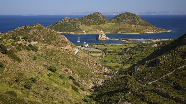 Hilly landscape with fields and coast, green and blue dominate the view, rocks of Kalikatsou, island of Tragonisi, Patoinos, organic viticulture, biodiversity garden, Patmos, Dodecanese, Greek Islands, Greece