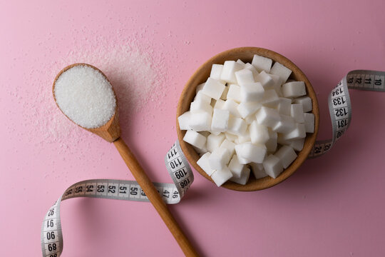 Measuring tape and white sugar on a colored background, top view.