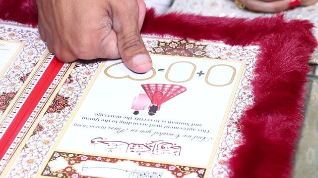 Close up of hands holding a traditional marriage certificate document Nikkah Nama decorated with red feathers with feathers intricate gold ornate marriage