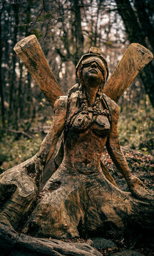 Vertical composition of a full carved wooden sculpture integrated with its original tree trunk base in the "Bosque Tallado" (Carved Forest), El Bols&oacute;n, Patagonia, Argentina.