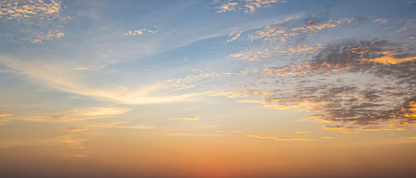 Beautiful sunset sky background with soft pastel orange light and clear blue clouds for panoramic travel mockup design