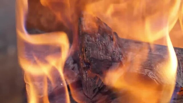 High-quality footage capturing the process of preparing a barbecue, showing hot charcoal pieces and wood chips burning with bright orange flames. The clip features glowing red embers providing consist