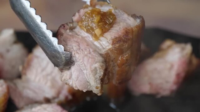 A detailed close-up shot of juicy, well-seasoned pork steaks and ribs being cooked on a barbecue grill. The footage captures rising steam and smoke, highlighting the tender texture and caramelization 