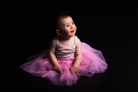 Baby girl wearing pink tutu looking up smiling