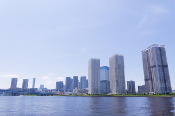 Tokyo Japan skyline of Toyosu waterfront featuring modern residential towers reflected across Tokyo Bay under a clear summer sky © minortica7