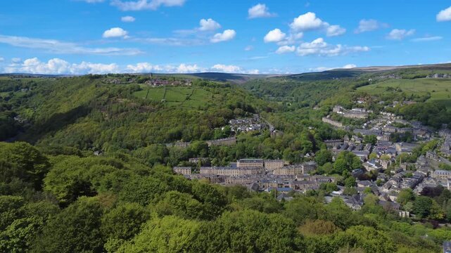 aerial panning view of hebden bridge and heptonstall in summer surrounded by trees and fields