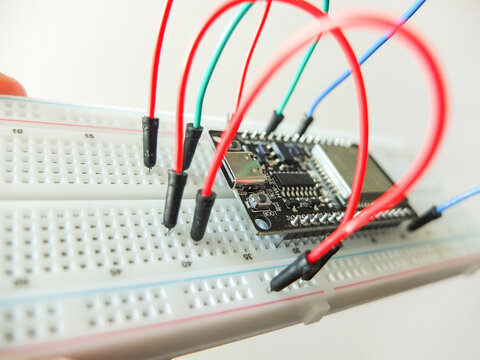 Microcontroller board with connected colorful jumper wires on electronic breadboard.