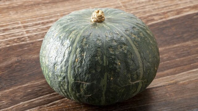 Fresh whole green pumpkin on wooden table with natural stem and ridged texture