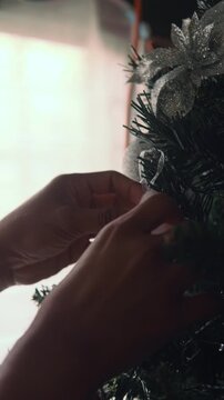Person's hands hanging ornament on christmas tree