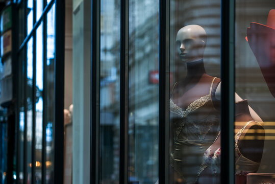 Mannequin wearing elegant lace lingerie in a luxury boutique storefront window with city reflections