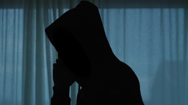 Hooded man silhouette making a suspicious phone call