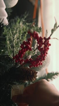 Person's hand decorating a traditional christmas tree with ornaments