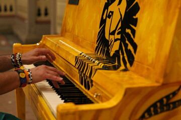 Close up of hands playing a vibrant hand-painted piano outdoors © Fabio