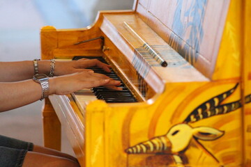 Close up of hands playing a vibrant hand-painted piano outdoors © Fabio