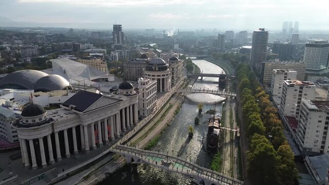 City square in Skopje with buildings, sculptures, and a bridge during midday