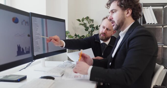 Coworkers managers meeting analytics strategy discussion planning. Two professionals review data and coordinate tasks in a bright office. Clear teamwork enables smart business choices.