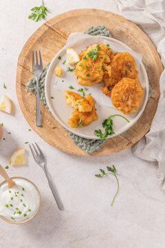 Crispy golden cod fritters on a rustic plate with fresh parsley, lemon, and a creamy dipping sauce, a perfect savory Mediterranean snack