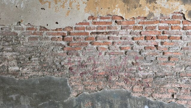 Ancient brick wall with cracked peeling plaster texture. Weathered antique red brick wall showcasing damaged plaster layers, perfect for historical backdrops. Rustic grunge exposed brick wall.