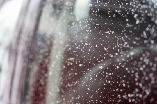 Close-up of a car window covered with scattered snowflakes and ice crystals.