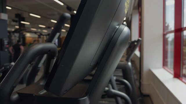 Close view of modern gym exercise machines lined beside bright windows in fitness center