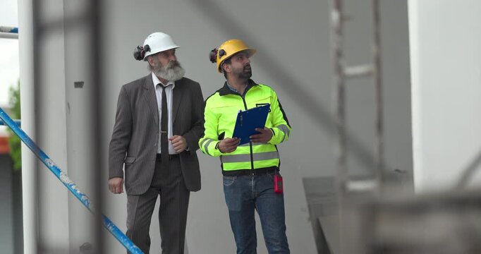 Engineer and businessman inspecting house construction site while discussing building project