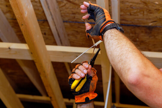 Worker uses pliers to cut wire while standing on construction site