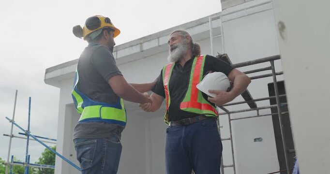 Two construction workers shaking hands closing a deal with agreement at house building site