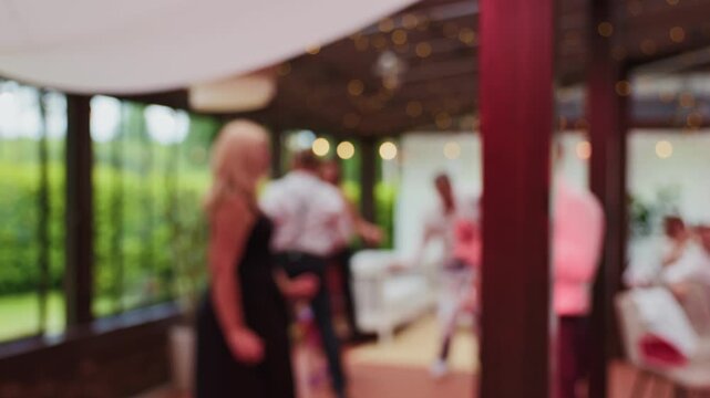Blurred guests mingling at elegant outdoor reception with warm string lights and soft evening atmosphere