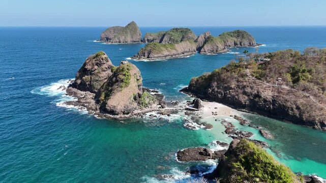 Stunning aerial footage of steep rocky cliffs and tropical islets surrounded by crystal-clear turquoise ocean waters