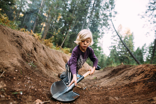 Boy Digging in Pine Forest