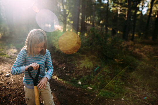 Girl Digging with Shovel in the Forest