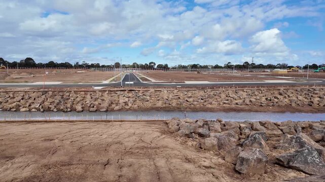 New roads and rock-lined drainage channel run through cleared, subdivided land prepared for house construction in outer suburban Werribee, Melbourne Australia. Urban development, land subdivision
