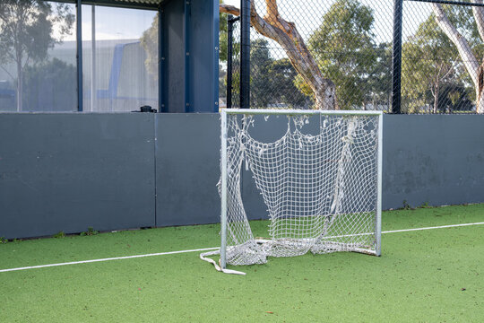 A weathered goal net with a torn edge stands on a synthetic sports field in suburban Melbourne Australia. ageing community sports facilities, council maintenance needs, and local infrastructure upkeep