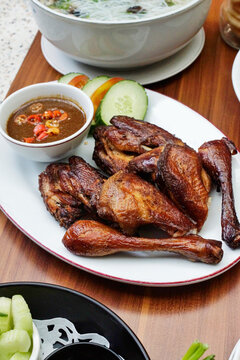 Indonesian ayam bakar grilled chicken with sweet soy glaze served with sambal chili sauce and fresh cucumber. Traditional Asian dish with rich caramelized texture.