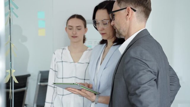 Business team collaborating on strategy, brainstorming ideas with post it notes on a glass board during an office meeting, planning effective project development