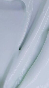Stirring beauty cream evenly using a metal tool. Vertical close up top view of cream being spread and smoothed with metal. Skincare application concept.