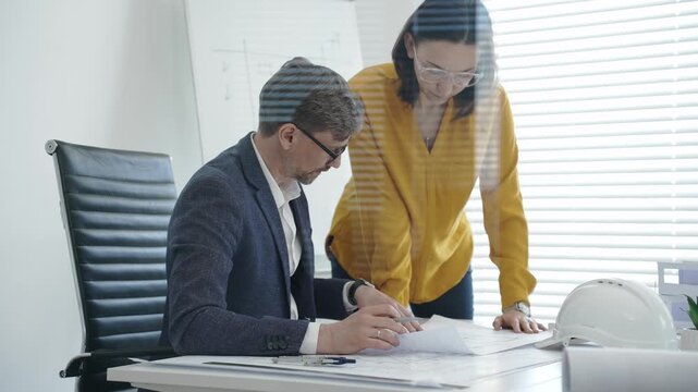 Architects and engineers reviewing blueprints and project plans at a desk, collaborating on design solutions and construction strategy in a modern professional office setting