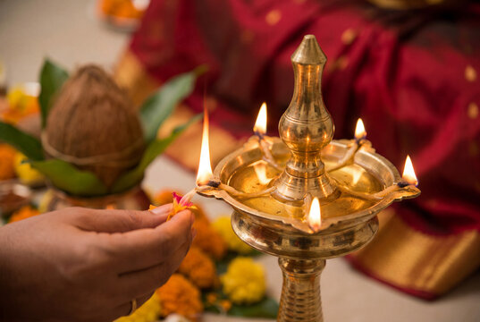 Hand lighting a traditional polished brass indian oil lamp during a festive celebration