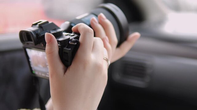 Hand holds camera inside car, ready to capture moments. Fingers steady, focused on framing shot. Lens points outward, anticipating next scene. Perfect for travel, vlog, or documentary projects