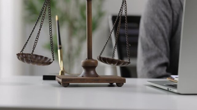 Scales of justice swaying on lawyer office desk, legal justice concept.