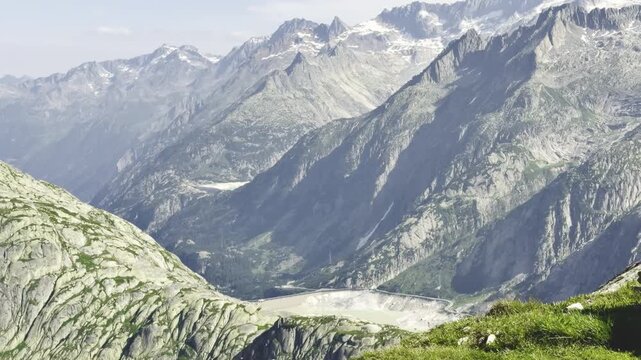 Slow motion view over a deep glacial valley with a reservoir and dam